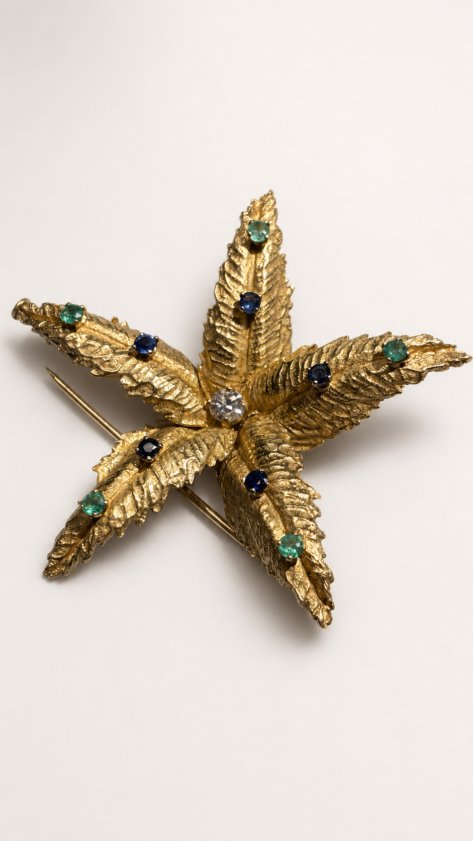 BOUCHERON brooch in yellow gold, emeralds, sapphires, and diamonds