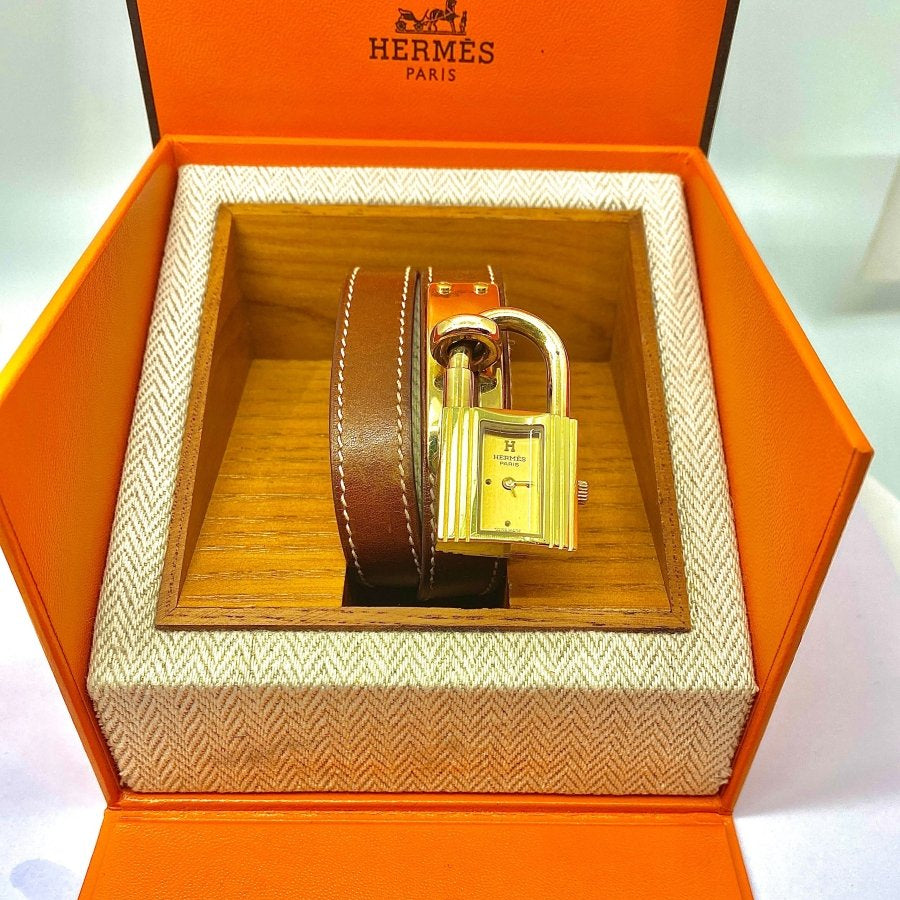 Montre Hermès Kelly , cadran PM plaqué or, double tour de poignet cuir marron - Castafiore